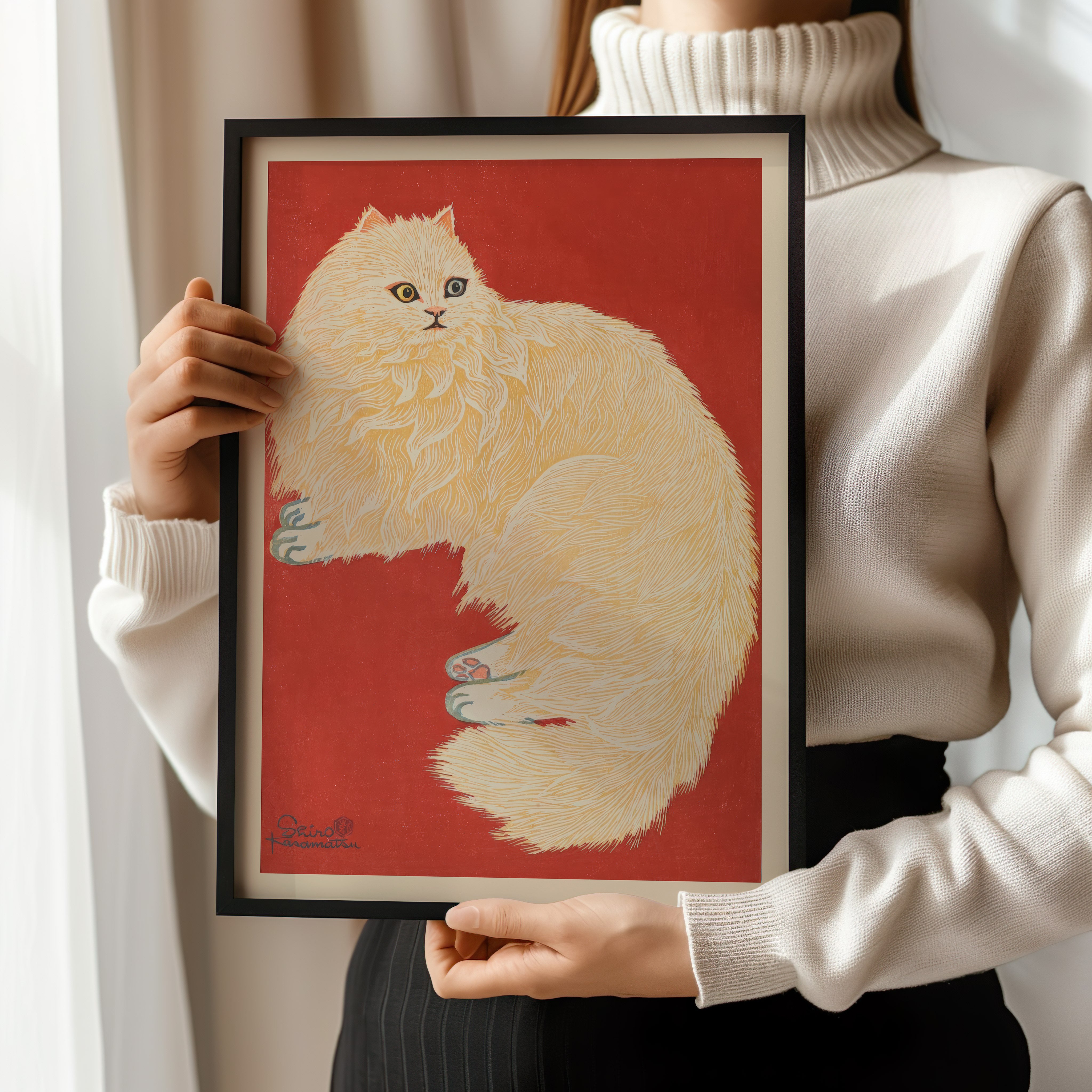 A person is holding a framed picture of a fluffy white cat against a red background.