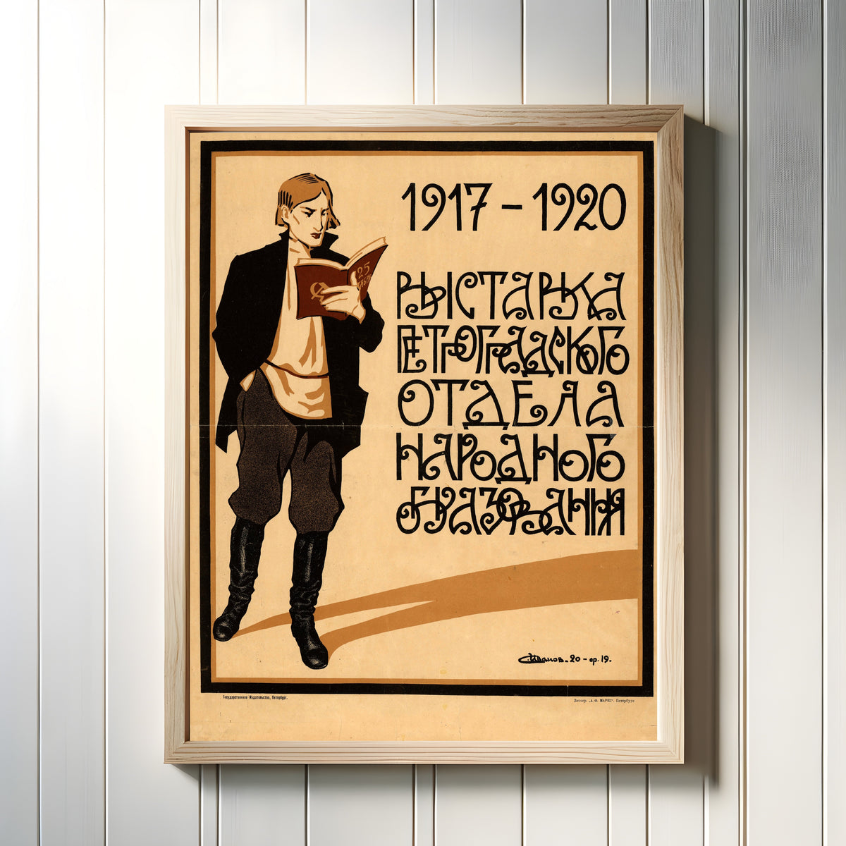 Framed art print of 1917-1920. Exhibition of the Petrograd Department of Public Education by Sergey Ivanov, in a light wood frame on a white panelled wall