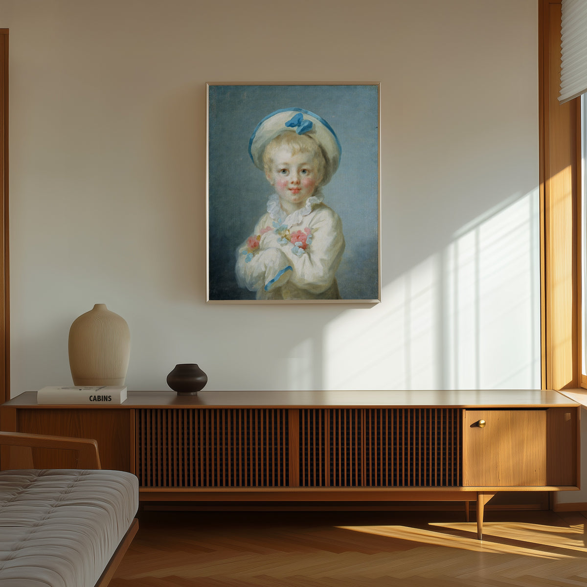 Framed art print of A Boy as Pierrot by Jean-Honoré Fragonard, in a thin light frame on a sunlit wall above a wooden sideboard