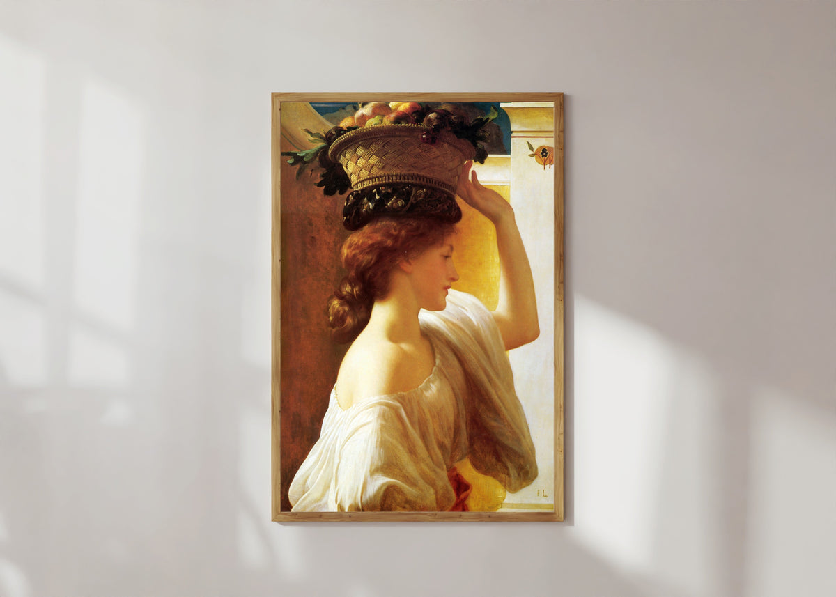 Framed art print of A Girl with a Basket of Fruit by Frederic Leighton, in a light wood frame on a sunlit white wall