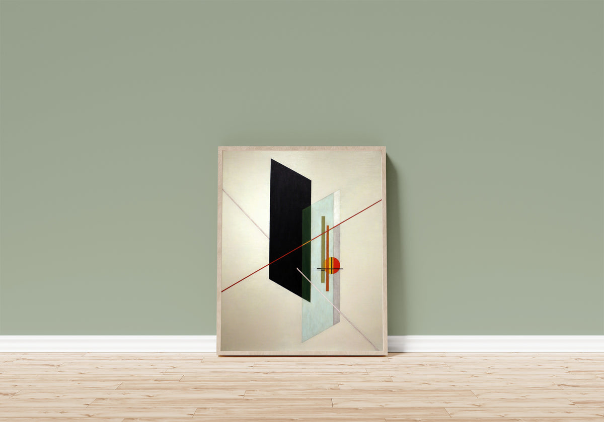 Framed art print of A IX by László Moholy-Nagy, in a light wood frame leaning on a sage green wall above a wooden floor