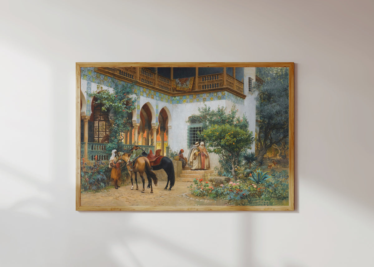 Framed art print of A North African Courtyard by Frederick Arthur Bridgman, in a light wood frame on a sunlit white wall