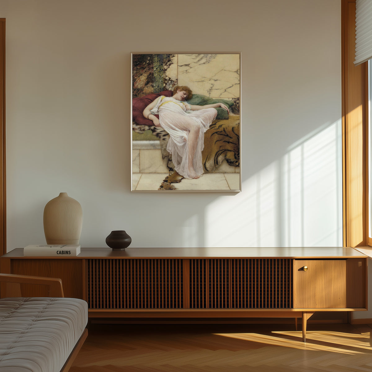 Framed art print of A Siesta by John William Godward, in a thin light frame on a sunlit wall above a wooden sideboard