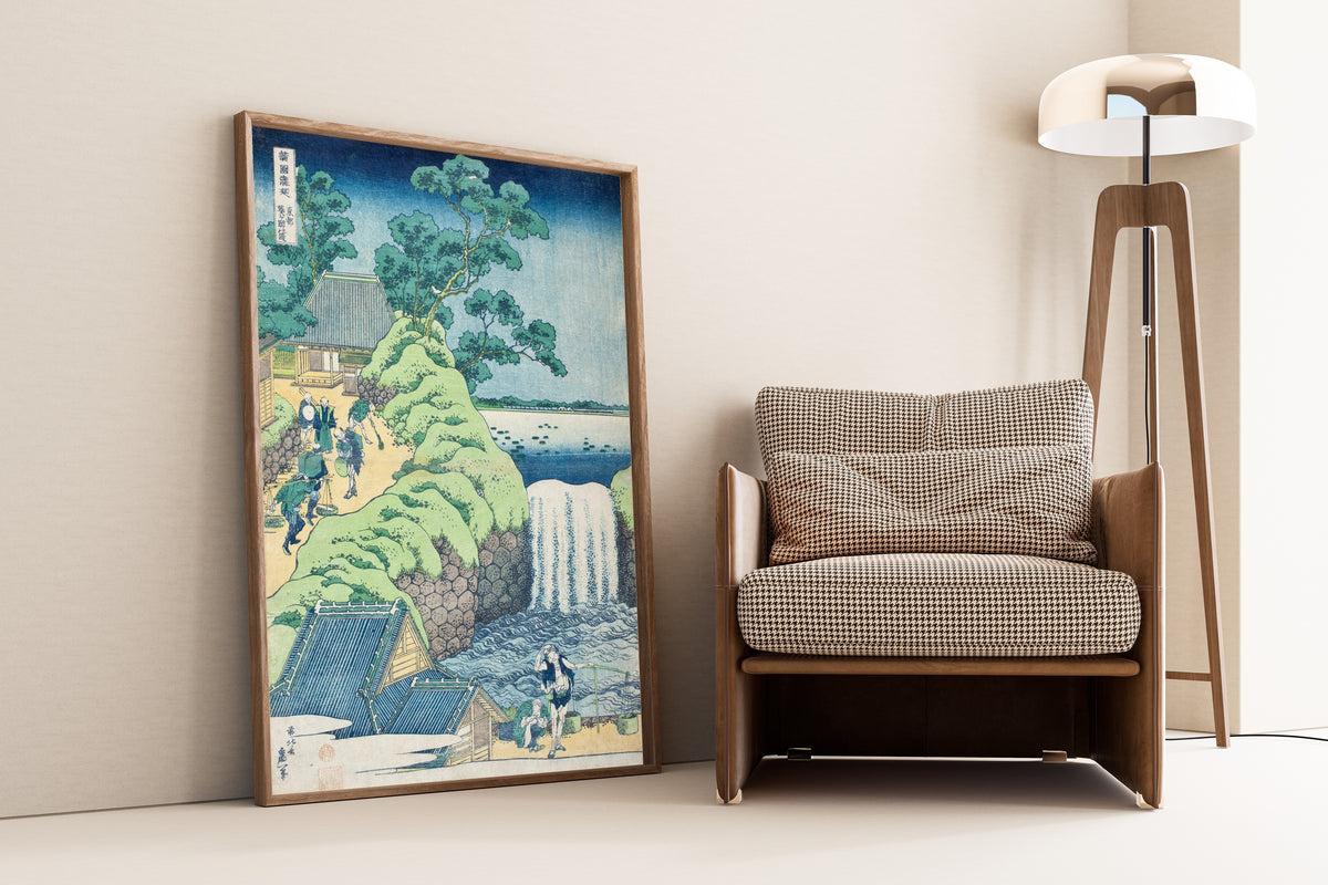 Framed art print of A Tour of the Waterfalls of the Provinces: Aoigaoka… by Katsushika Hokusai, leaning against a wall beside an armchair and a floor lamp
