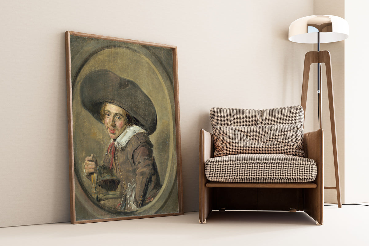 Framed art print of A Young Man in a Large Hat by Frans Hals, leaning against a wall beside an armchair and a floor lamp