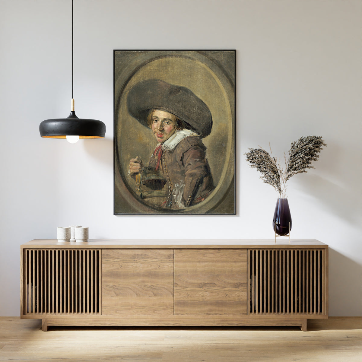 Framed art print of A Young Man in a Large Hat by Frans Hals, above a slatted wood sideboard