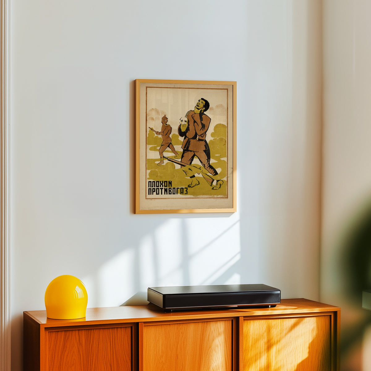 Framed art print of A bad gas mask, in a light wood frame on a white wall above an orange sideboard
