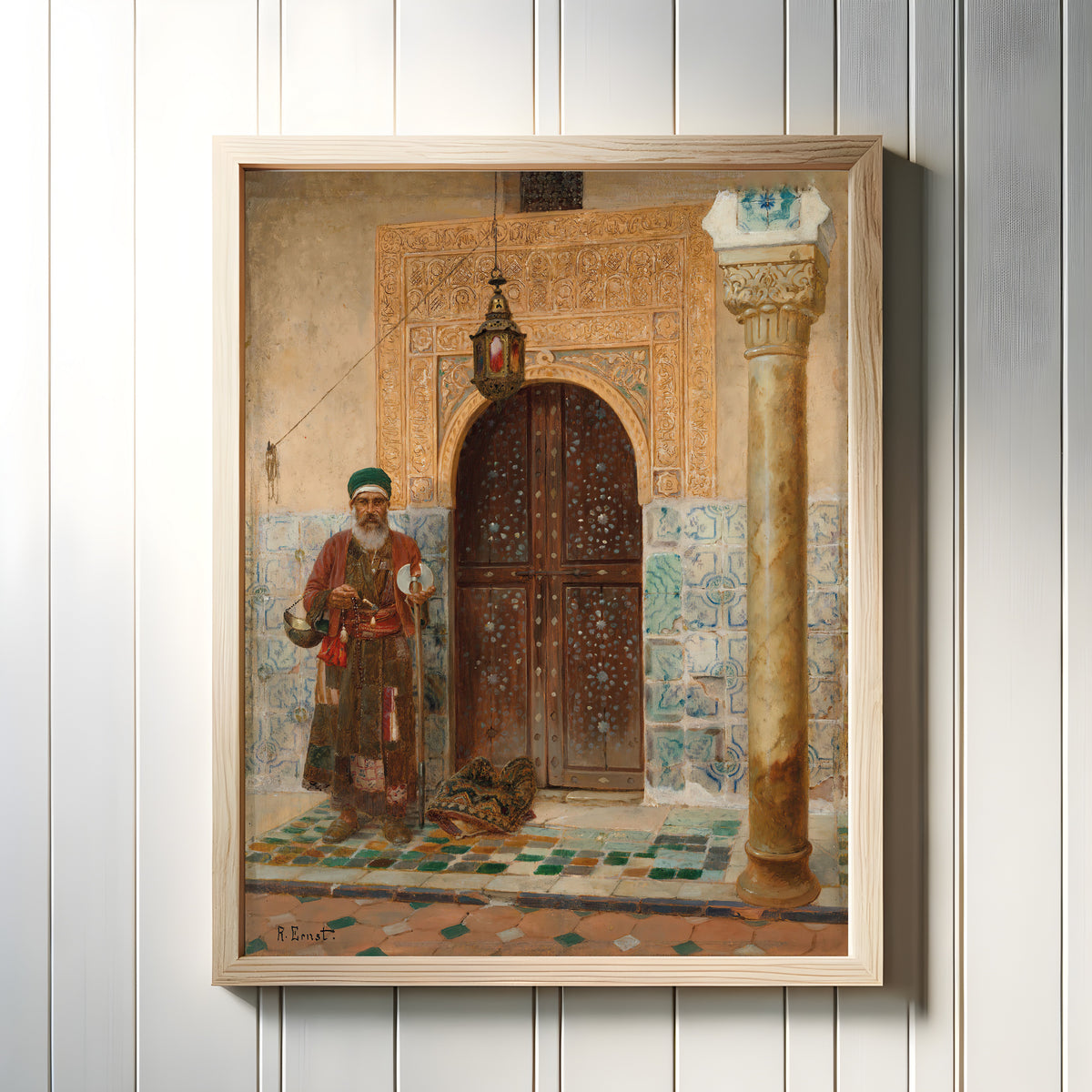 Framed art print of A holy man by an entrance by Rudolf Ernst, in a light wood frame on a white panelled wall