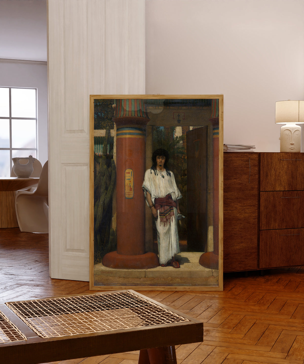 Framed art print of An Egyptian in a Doorway by Lawrence Alma-Tadema, in a light wood frame leaning in a warm room with a parquet floor