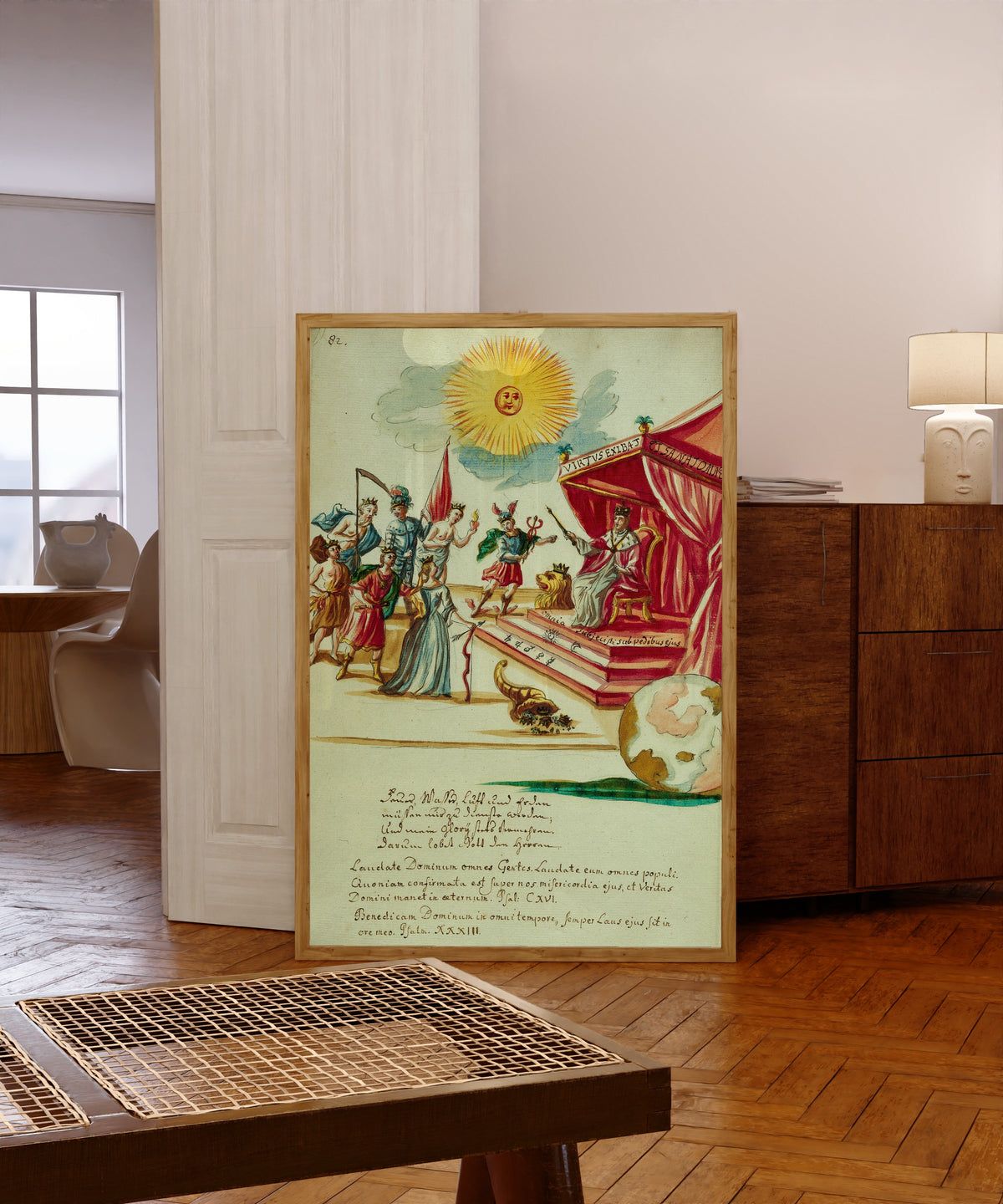 Framed art print of An Enthroned King Receiving Tribute beneath a… by Thesaurus Thesaurorum, in a light wood frame leaning in a warm room with a parquet floor
