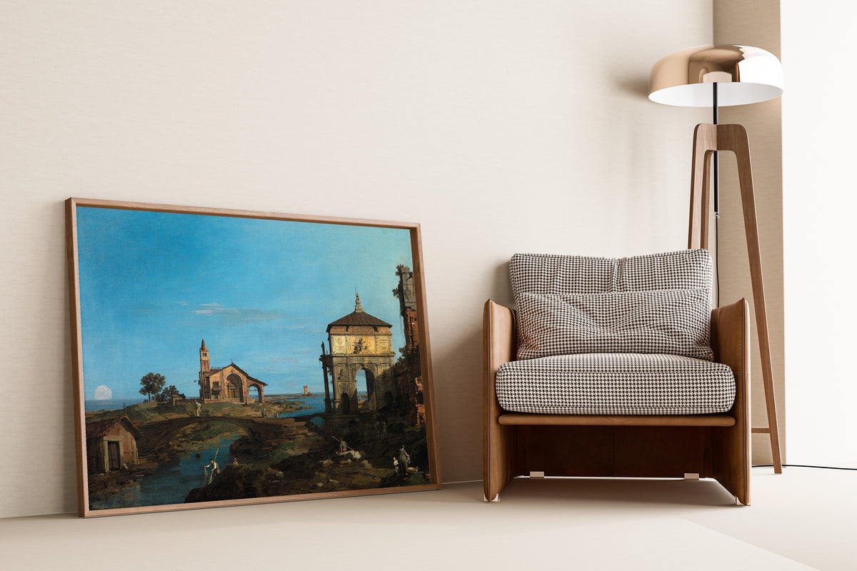 Framed art print of An Island in the Lagoon with a Gateway and a Church by Canaletto, leaning against a wall beside an armchair and a floor lamp
