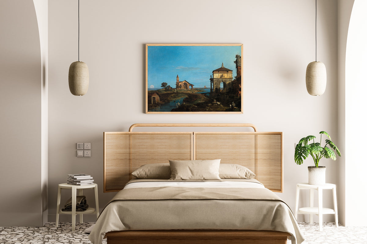 Framed art print of An Island in the Lagoon with a Gateway and a Church by Canaletto, above a cane-headboard bed