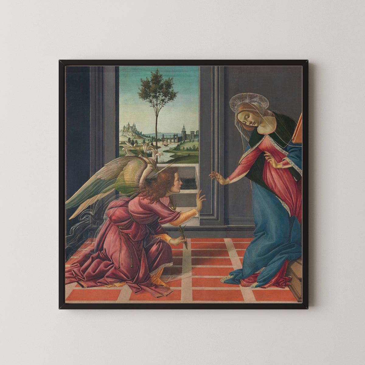 Framed art print of Annunciation by Sandro Botticelli, in a black frame on a pale wall