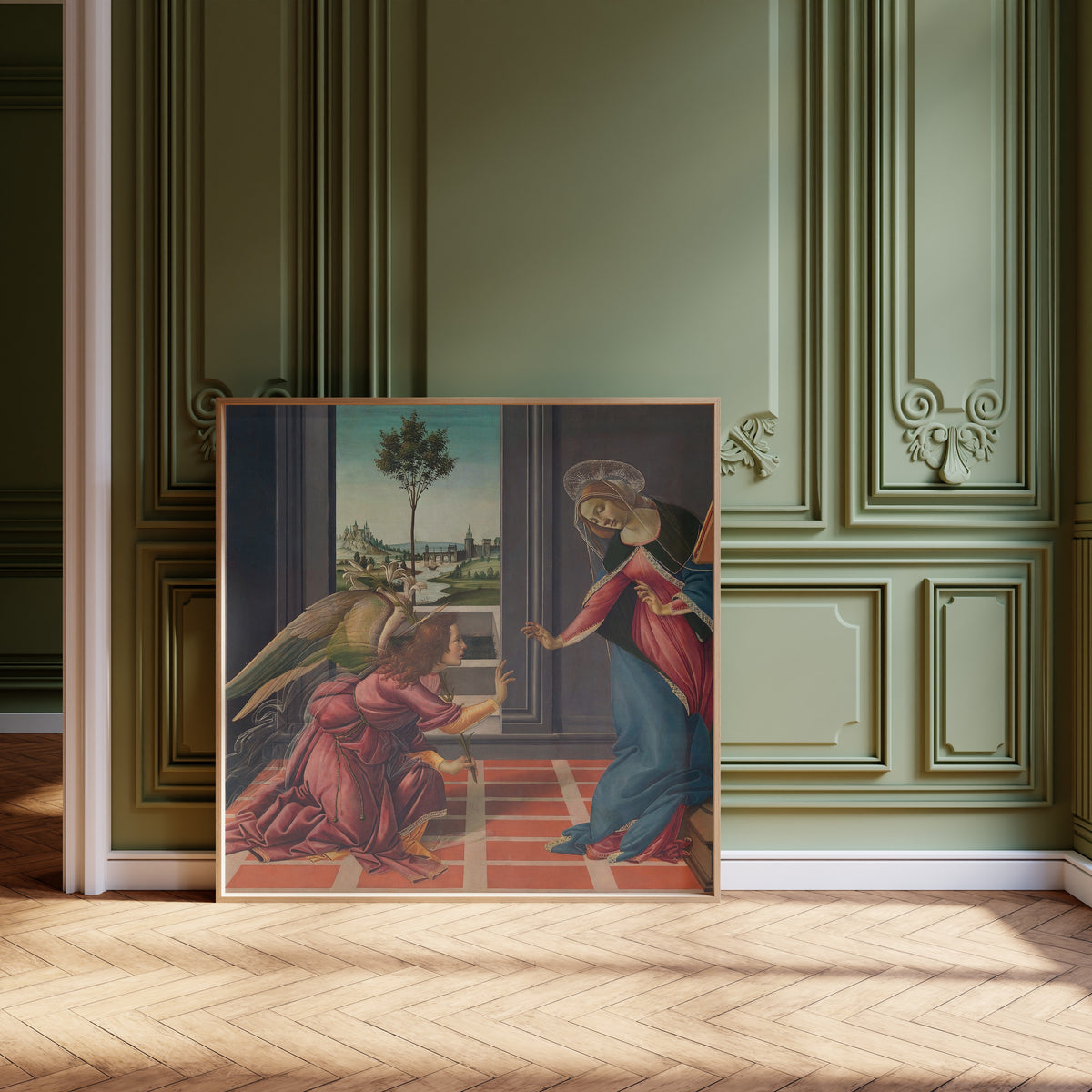 Framed art print of Annunciation by Sandro Botticelli, leaning against olive-green panelling on a herringbone floor