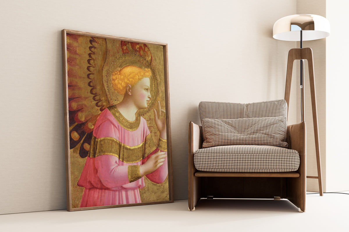 Framed art print of Annunciatory Angel by Fra Angelico, leaning against a wall beside an armchair and a floor lamp