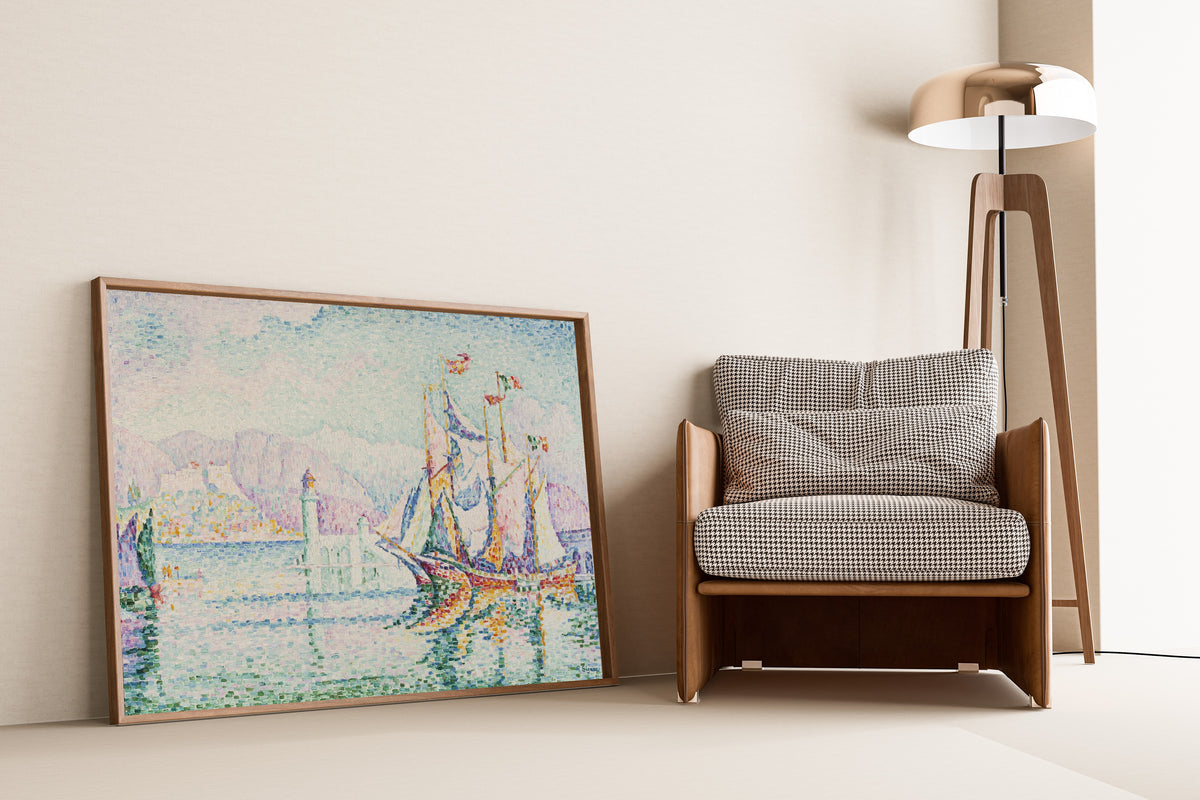Framed art print of Antibes, Morning by Paul Signac, leaning against a wall beside an armchair and a floor lamp