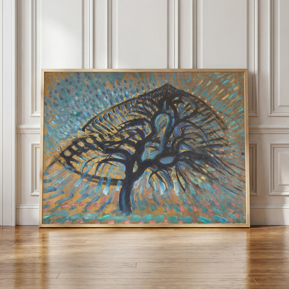 Framed art print of Apple Tree, Pointillist Version by Piet Mondrian, in a light wood frame leaning against a panelled white wall