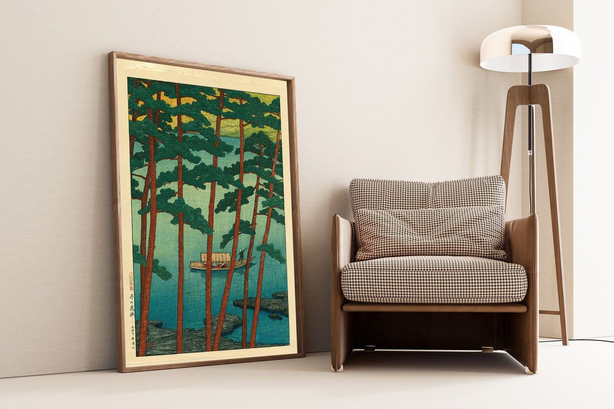Framed art print of Arashiyama in Winter by Kawase Hasui, leaning against a wall beside an armchair and a floor lamp