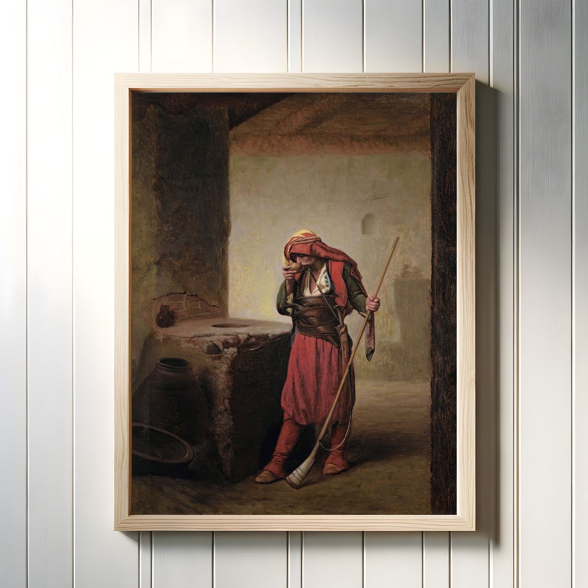 Framed art print of Arnaut Drinking by Jean-Léon Gérôme, in a light wood frame on a white panelled wall