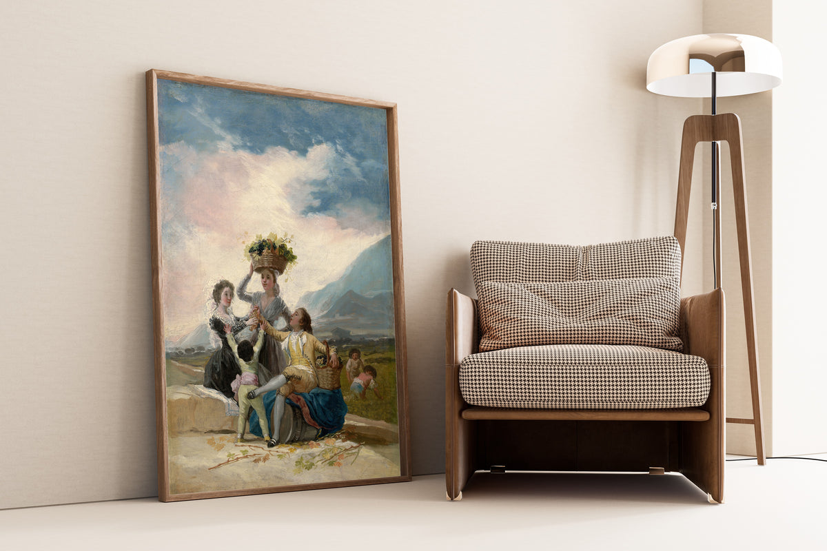 Framed art print of Autumn by Francisco de Goya, leaning against a wall beside an armchair and a floor lamp