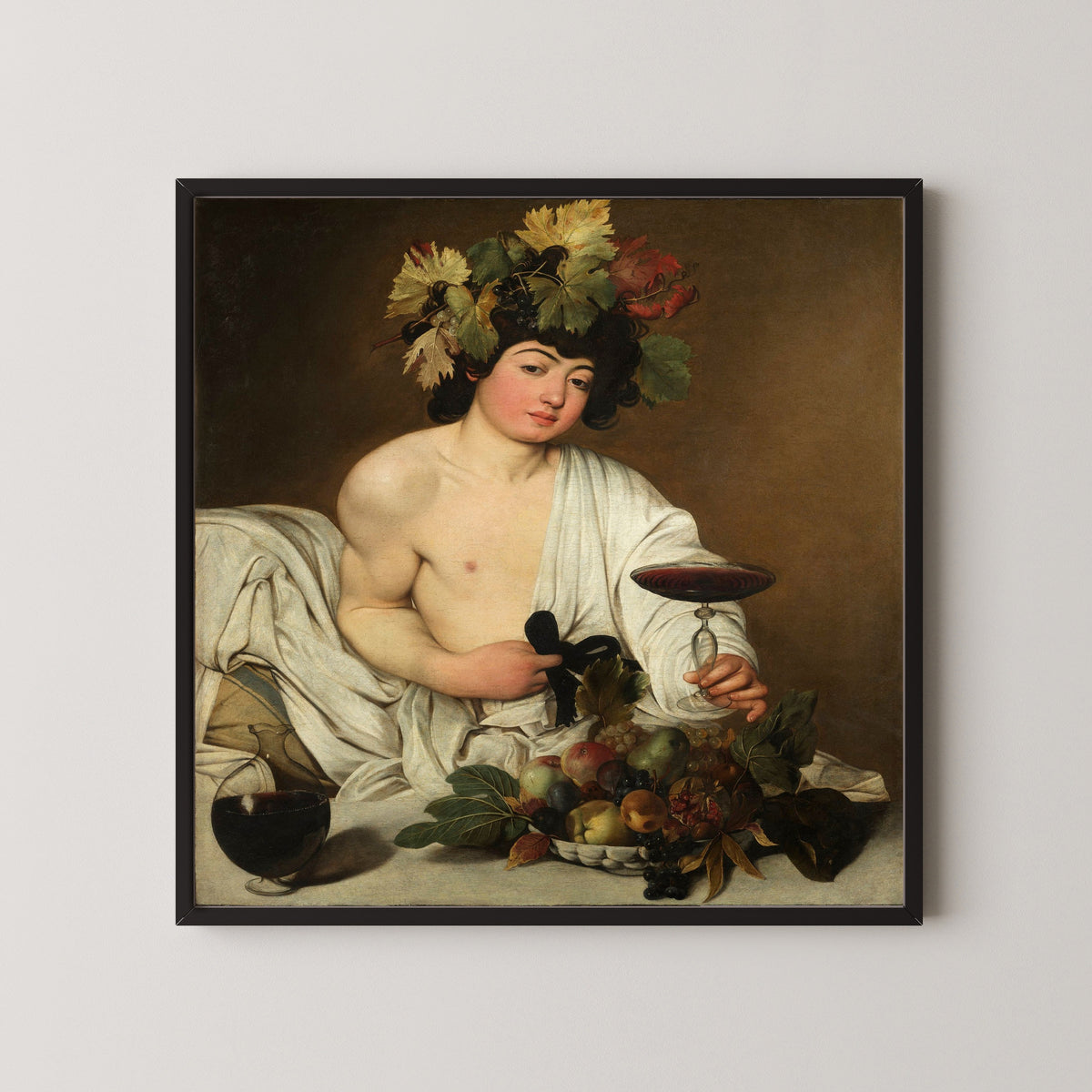 Framed art print of Bacchus by Caravaggio, in a black frame on a pale wall