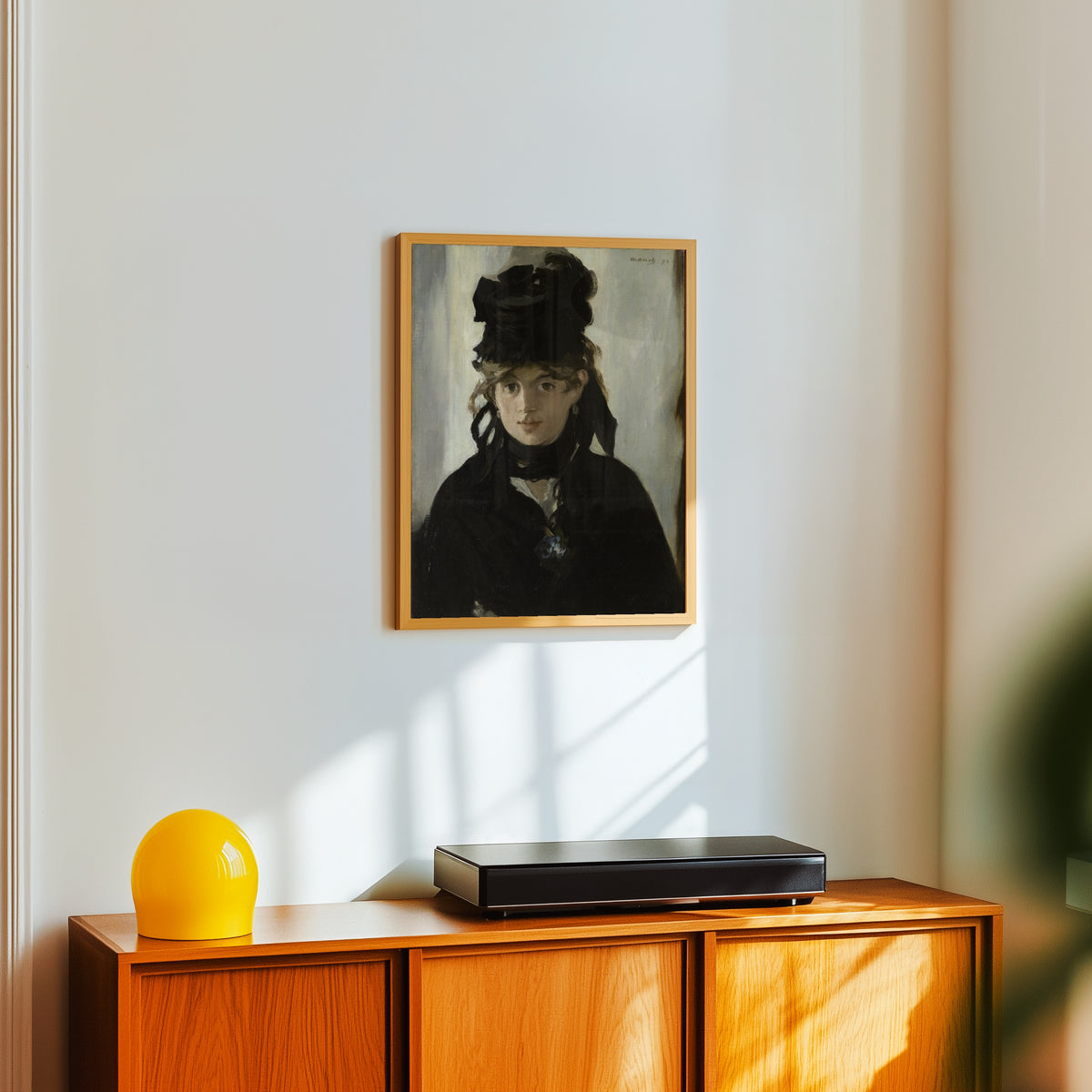 Framed art print of Berthe Morisot with a Bouquet of Violets by Édouard Manet, in a light wood frame on a white wall above an orange sideboard