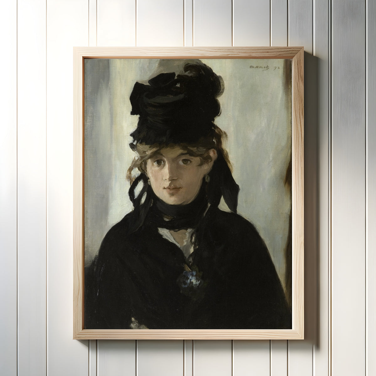 Framed art print of Berthe Morisot with a Bouquet of Violets by Édouard Manet, in a light wood frame on a white panelled wall