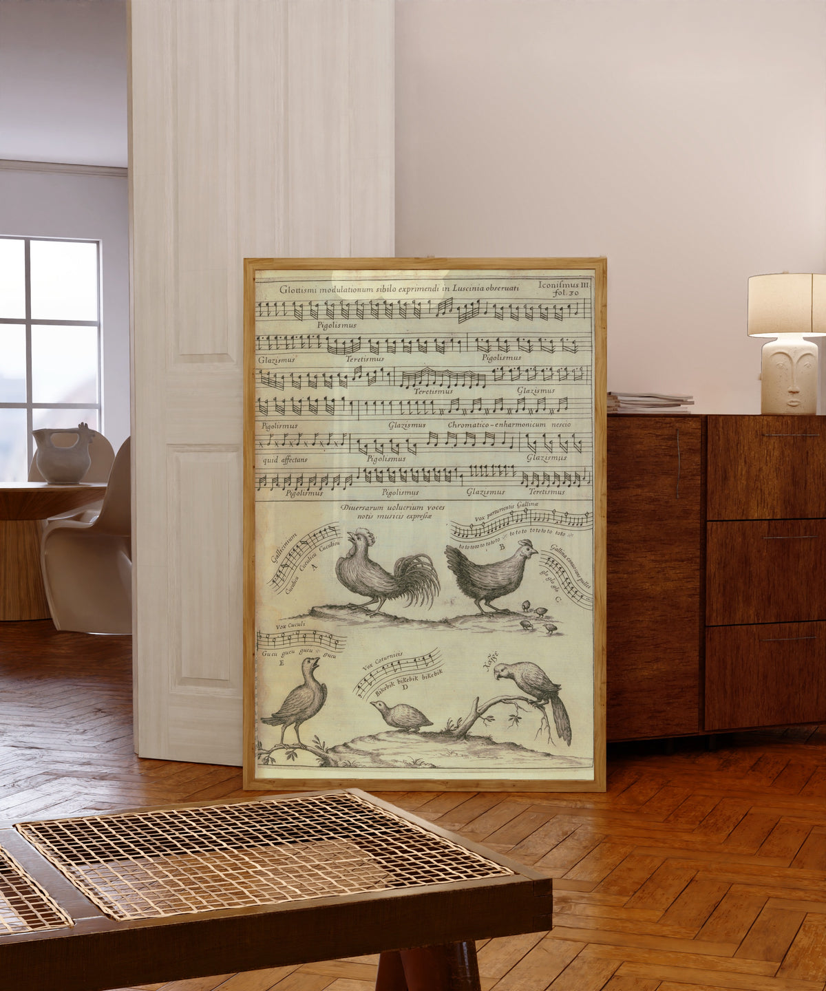 Framed art print of Birdsong Notated in Music (Musurgia Universalis) by Athanasius Kircher, in a light wood frame leaning in a warm room with a parquet floor