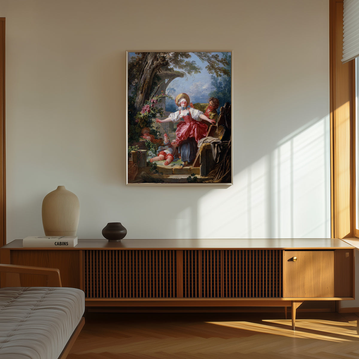 Framed art print of Blind-Man’s Buff by Jean-Honoré Fragonard, in a thin light frame on a sunlit wall above a wooden sideboard
