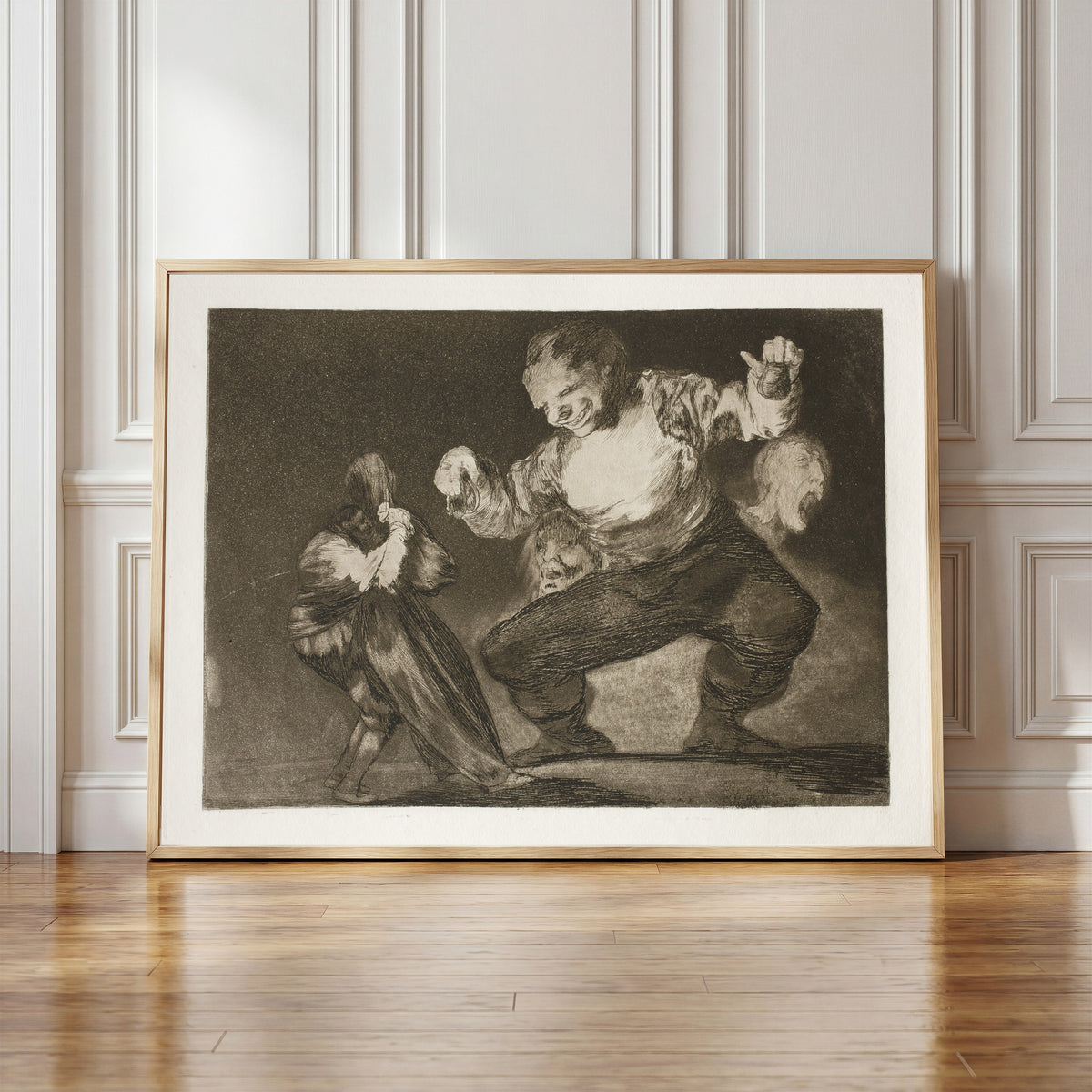 Framed art print of Bobalicón (Simpleton), from Los Disparates by Francisco de Goya, in a light wood frame leaning against a panelled white wall