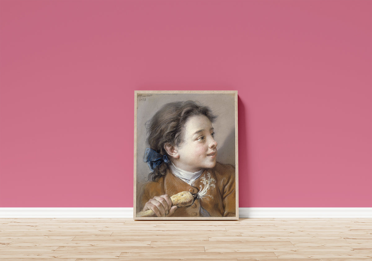 Framed art print of Boy with a Carrot by François Boucher, in a light wood frame leaning on a pink wall above a wooden floor