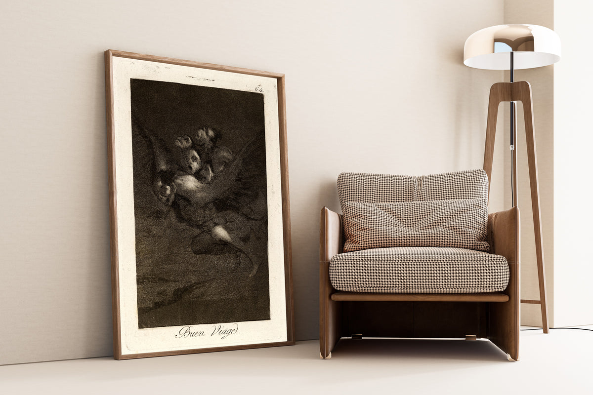 Framed art print of Buen Viage (Bon Voyage), Los Caprichos, Plate 64 by Francisco de Goya, leaning against a wall beside an armchair and a floor lamp