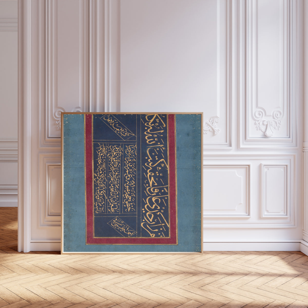 Framed art print of Calligraphy (Gold on Indigo) by Ahmad al-Husaini, leaning against pale pink panelling on a herringbone floor