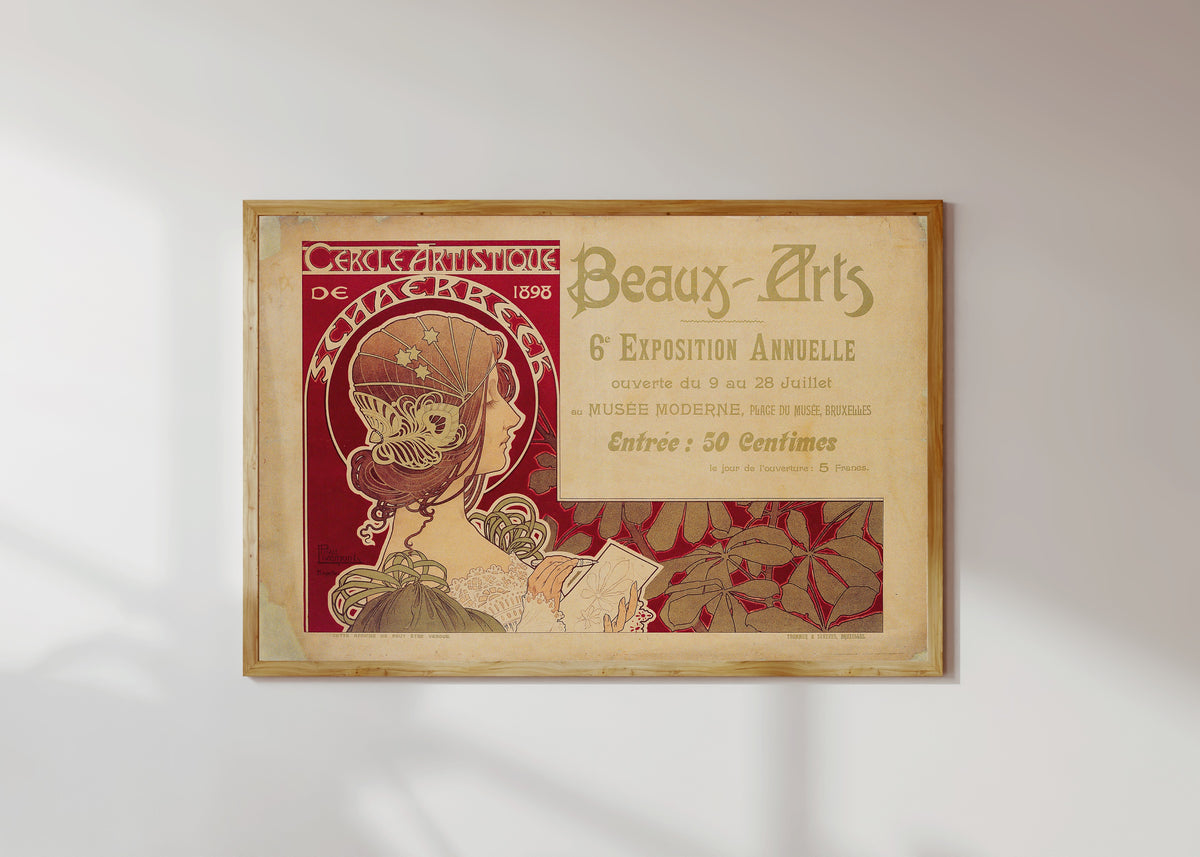 Framed art print of Cercle Artistique de Schaerbeek (1898) by Henri Privat-Livemont, in a light wood frame on a sunlit white wall