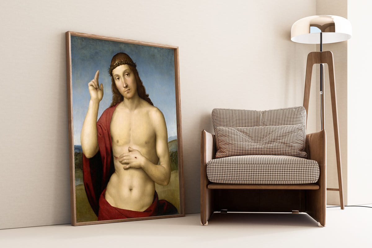 Framed art print of Christ Blessing (Pax Vobiscum) by Raphael, leaning against a wall beside an armchair and a floor lamp