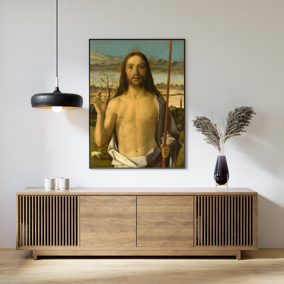 Framed art print of Christ Blessing by Giovanni Bellini, above a slatted wood sideboard
