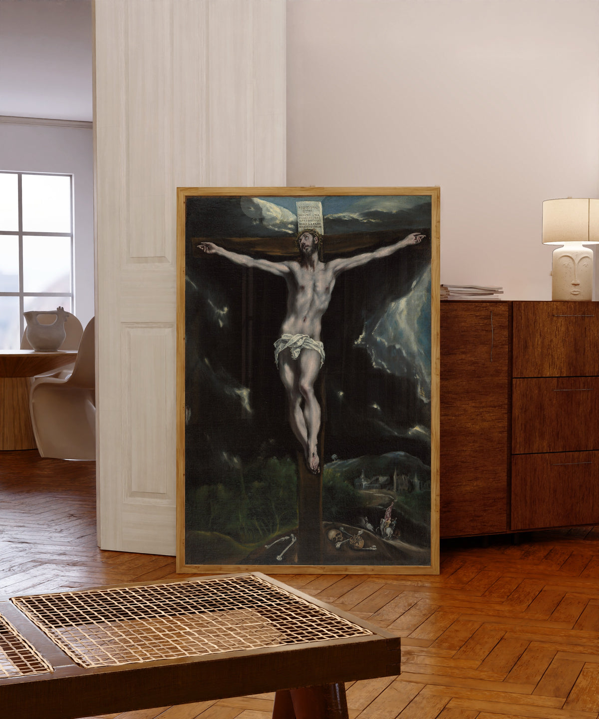 Framed art print of Christ on the Cross by El Greco, in a light wood frame leaning in a warm room with a parquet floor