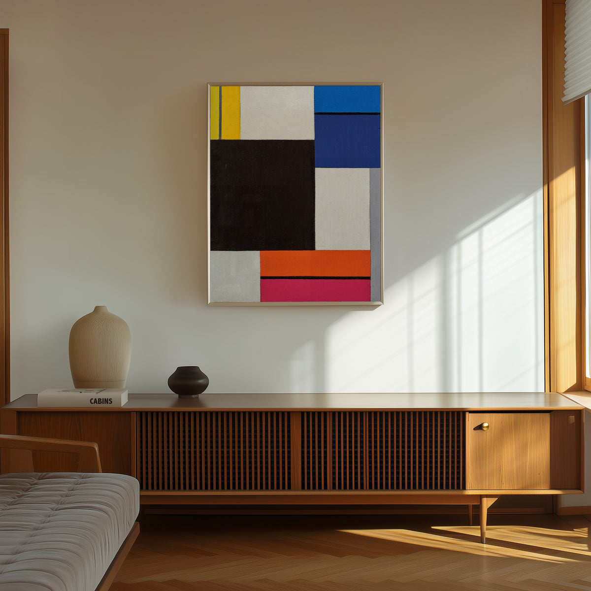 Framed art print of Composition XXI by Theo van Doesburg, in a thin light frame on a sunlit wall above a wooden sideboard