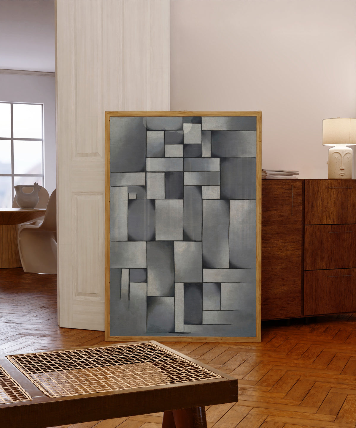 Framed art print of Composition in Gray (Rag-time). by Theo van Doesburg, in a light wood frame leaning in a warm room with a parquet floor