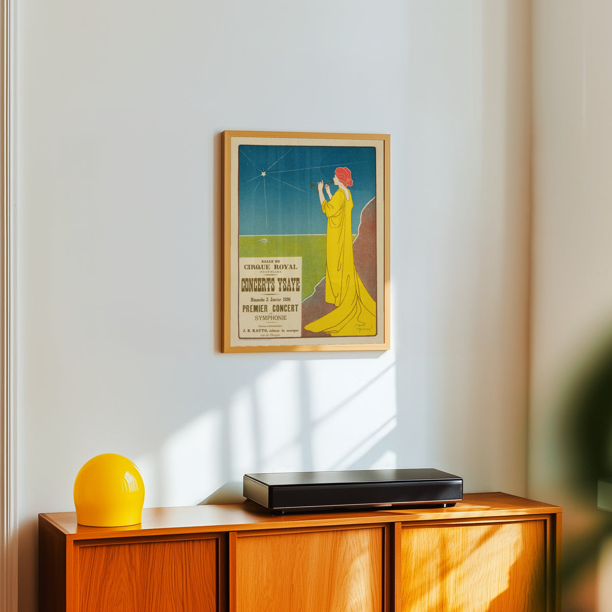 Framed art print of Concerts Ysaÿe by Henri Meunier, in a light wood frame on a white wall above an orange sideboard