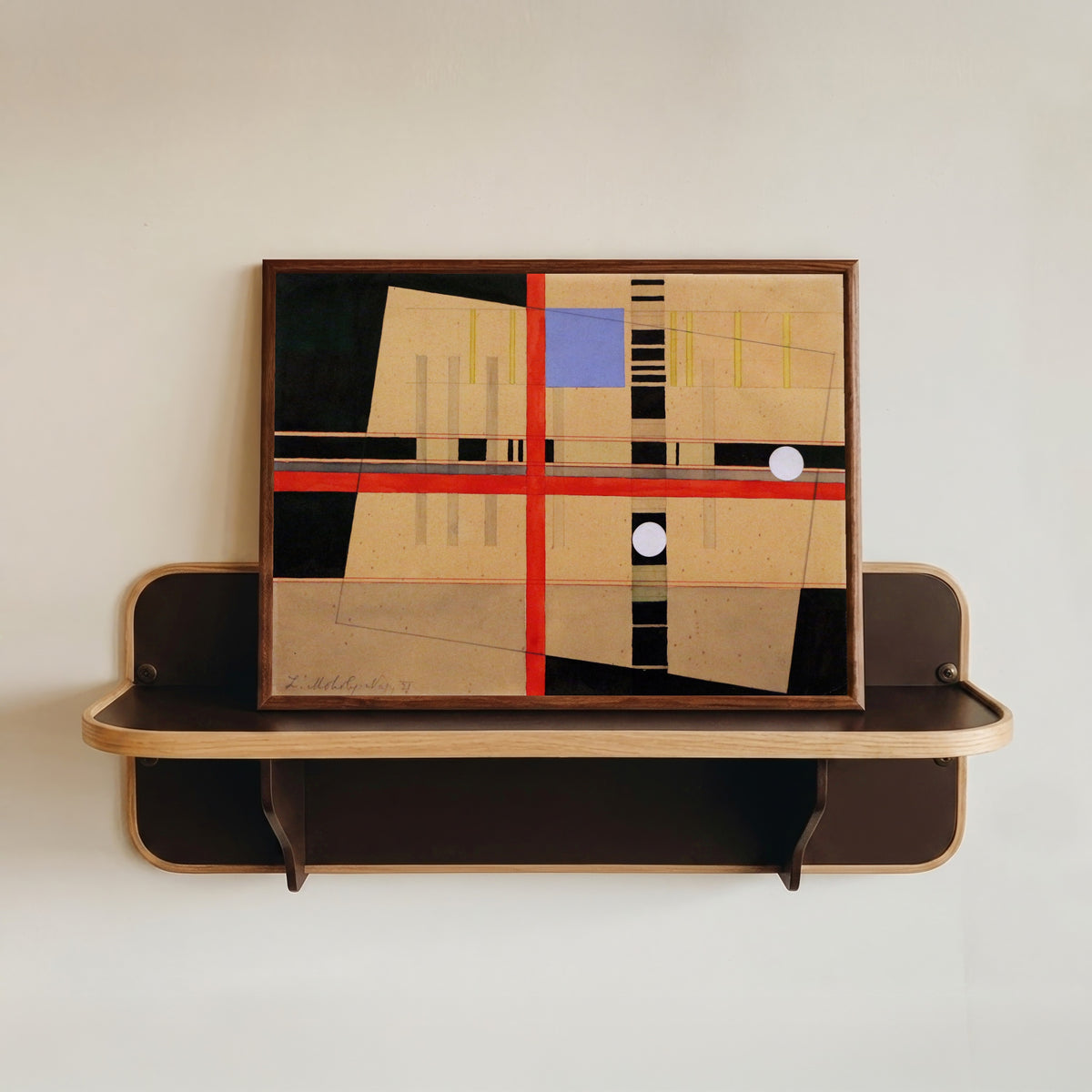 Framed art print of Croce rossa e palle bianche by László Moholy-Nagy, in a dark wood frame resting on a wall shelf