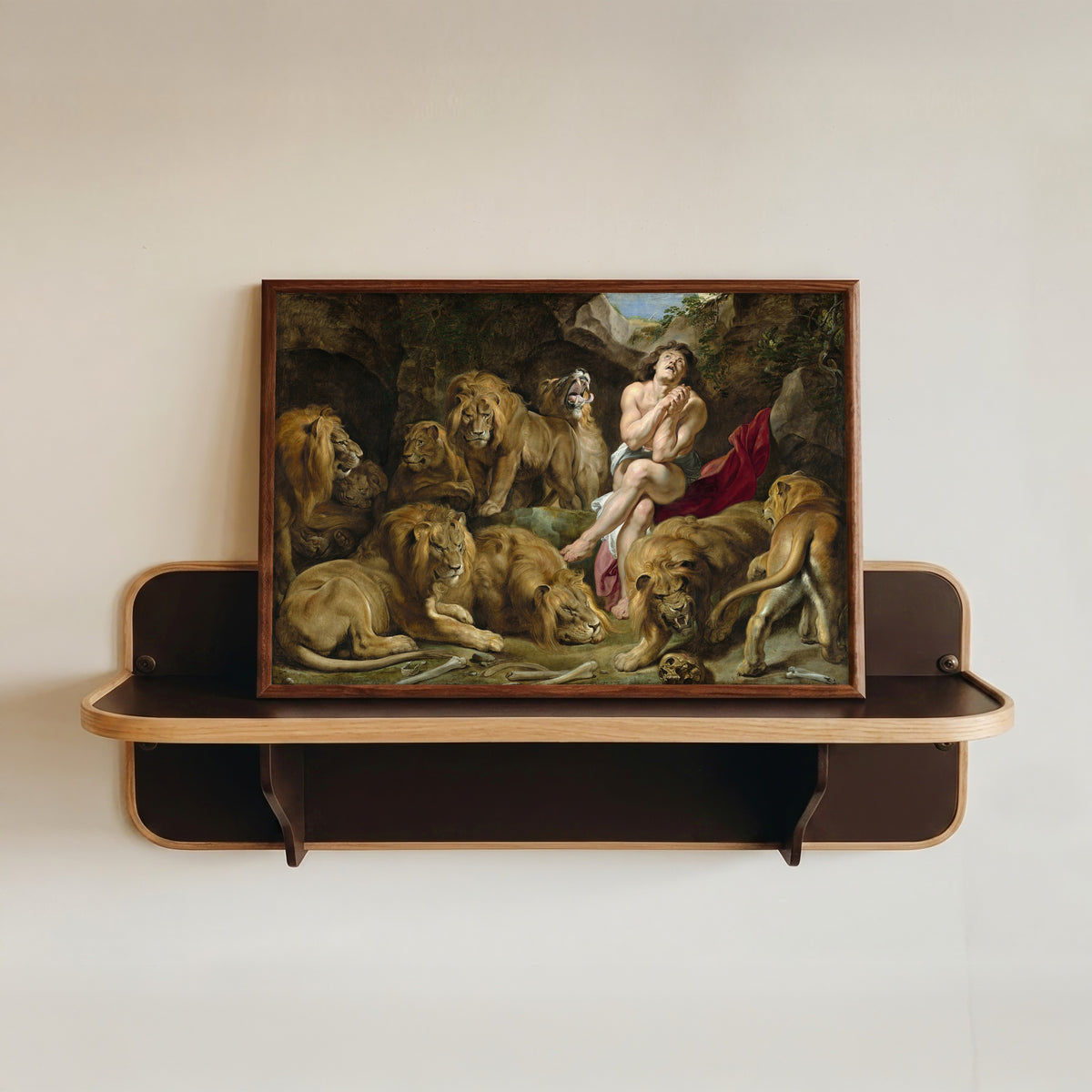 Framed art print of Daniel in the Lions' Den by Peter Paul Rubens, in a dark wood frame resting on a wall shelf