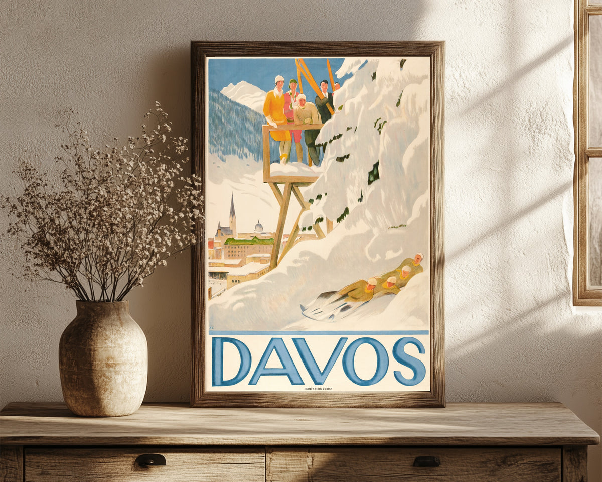 Framed art print of Davos by Emil Cardinaux, in a dark wood frame leaning on a rustic console beside dried flowers