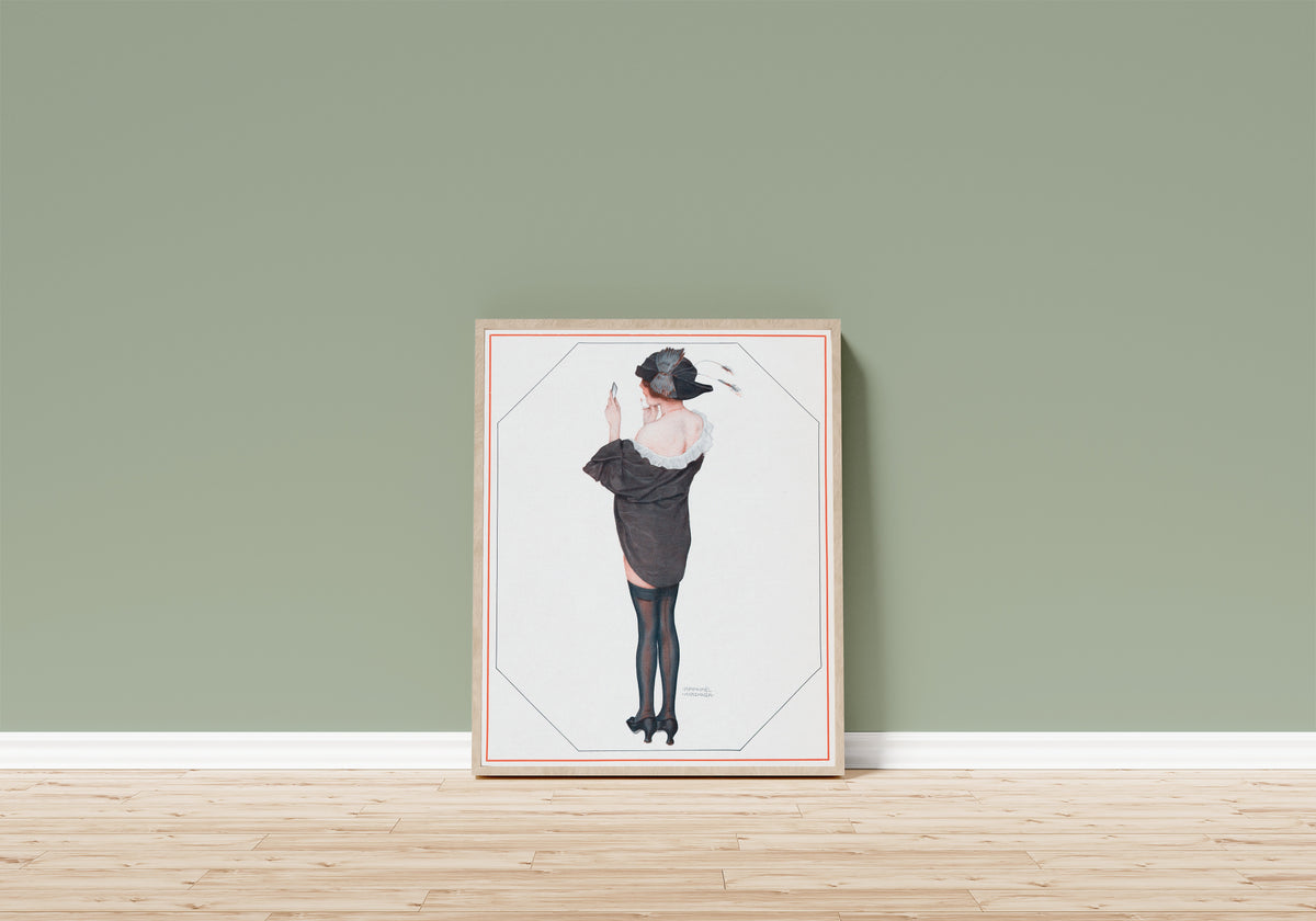 Framed art print of De la Brune à la Blonde, Pl. 2: Entre Deux… by Raphael Kirchner, in a light wood frame leaning on a sage green wall above a wooden floor
