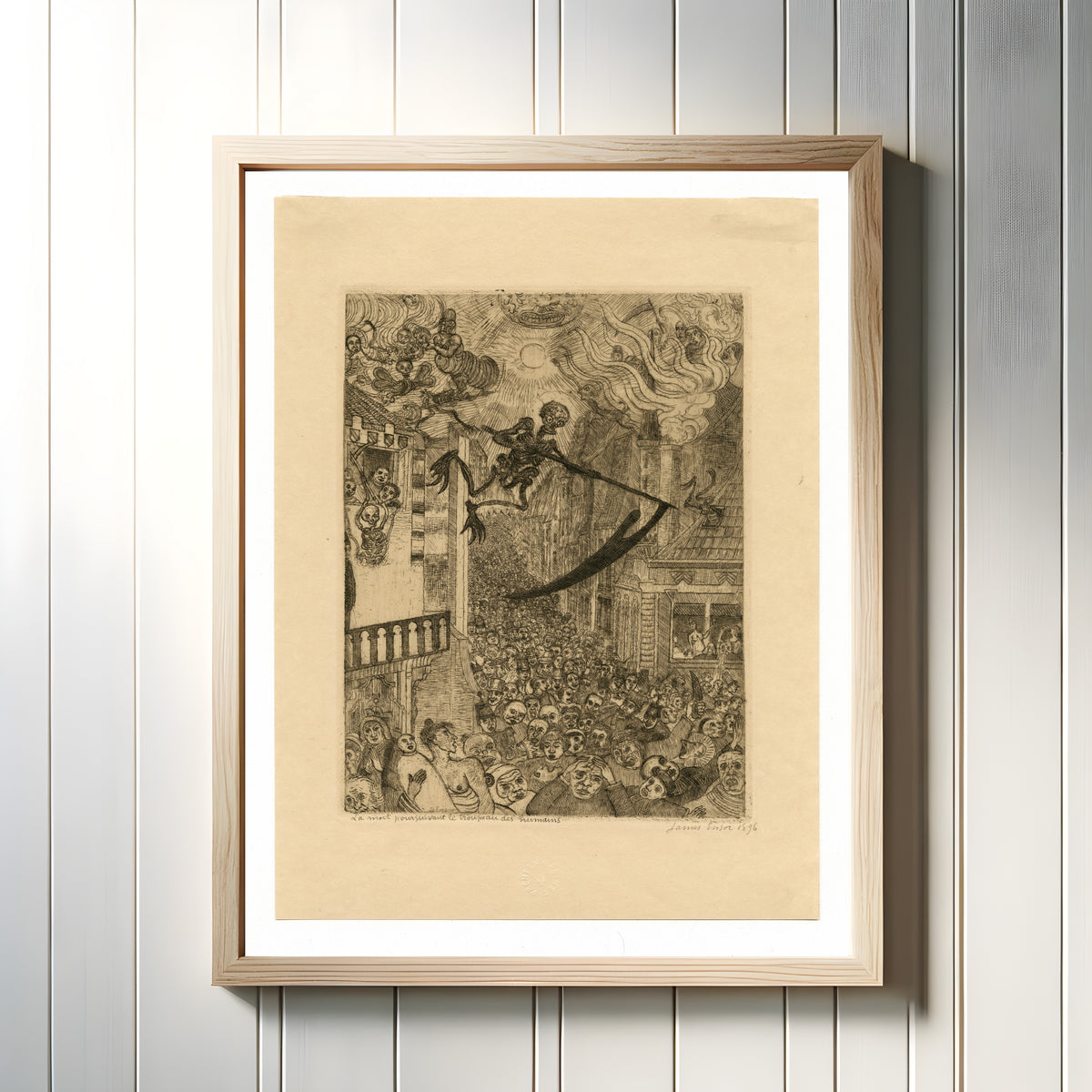 Framed art print of Death Pursuing the Human Herd (La mort poursuivant le troupeau des humains) by James Ensor, in a light wood frame on a white panelled wall