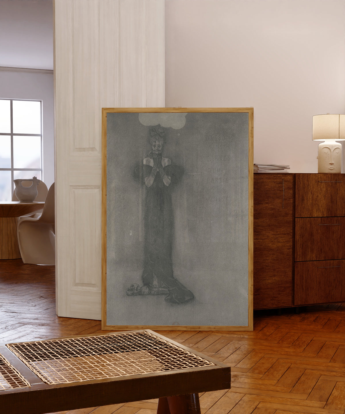 Framed art print of Dessous des cartes d'une partie de whist (2nd state) by Félicien Rops, in a light wood frame leaning in a warm room with a parquet floor