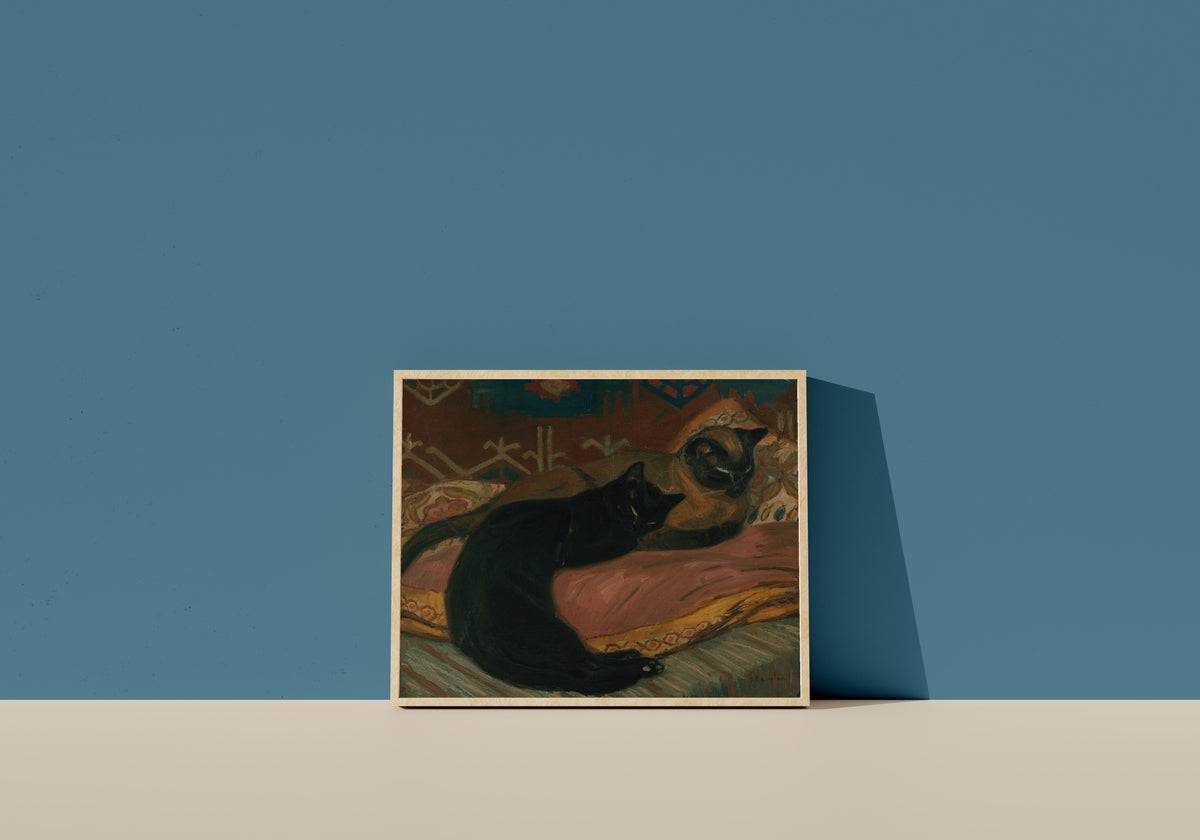 Framed art print of Deux chats couchés sur un canapé by Théophile Steinlen, in a light wood frame leaning on a blue wall