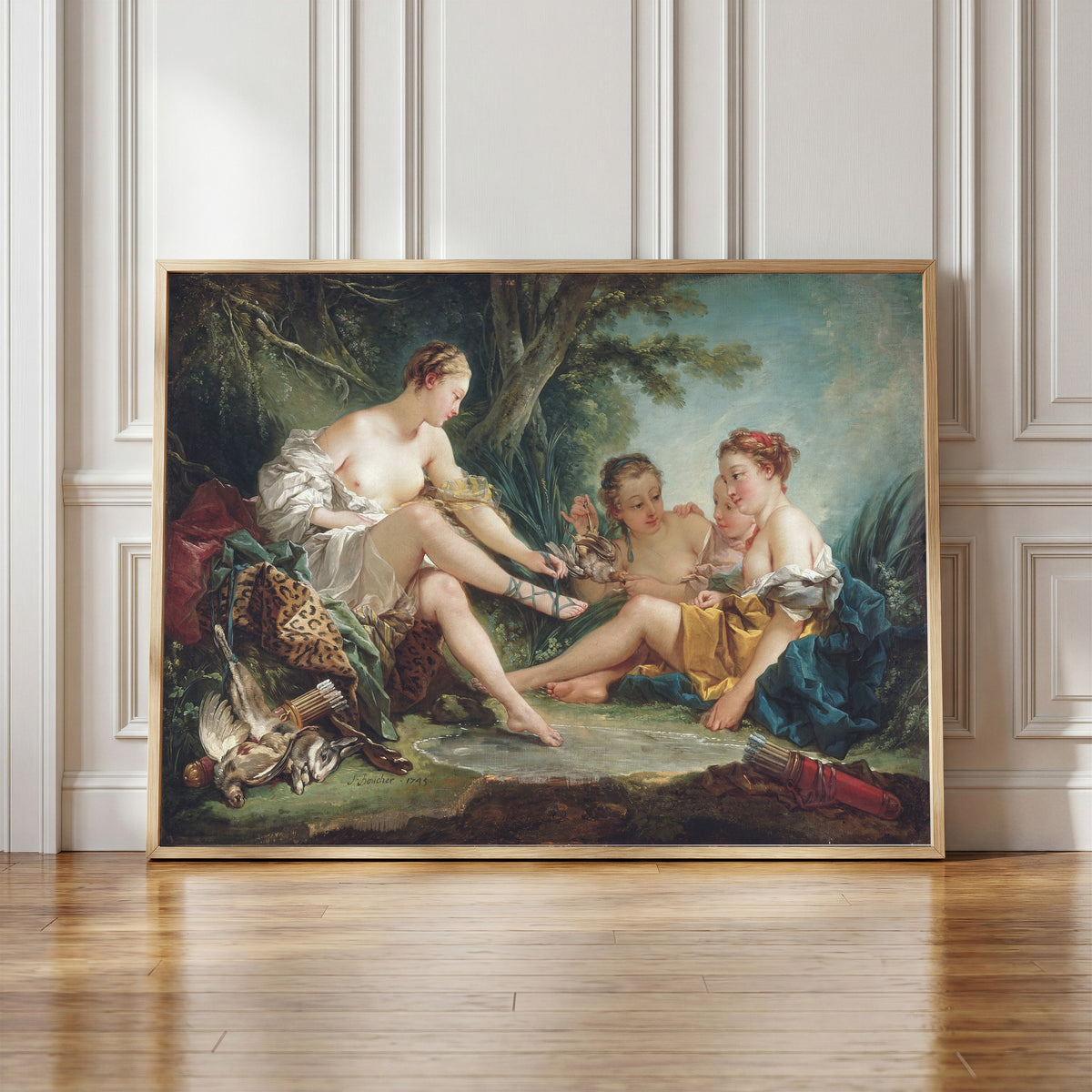 Framed art print of Diana Returning from the Hunt by François Boucher, in a light wood frame leaning against a panelled white wall