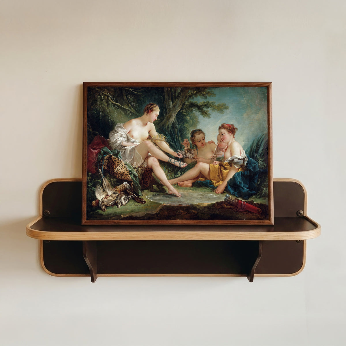 Framed art print of Diana Returning from the Hunt by François Boucher, in a dark wood frame resting on a wall shelf