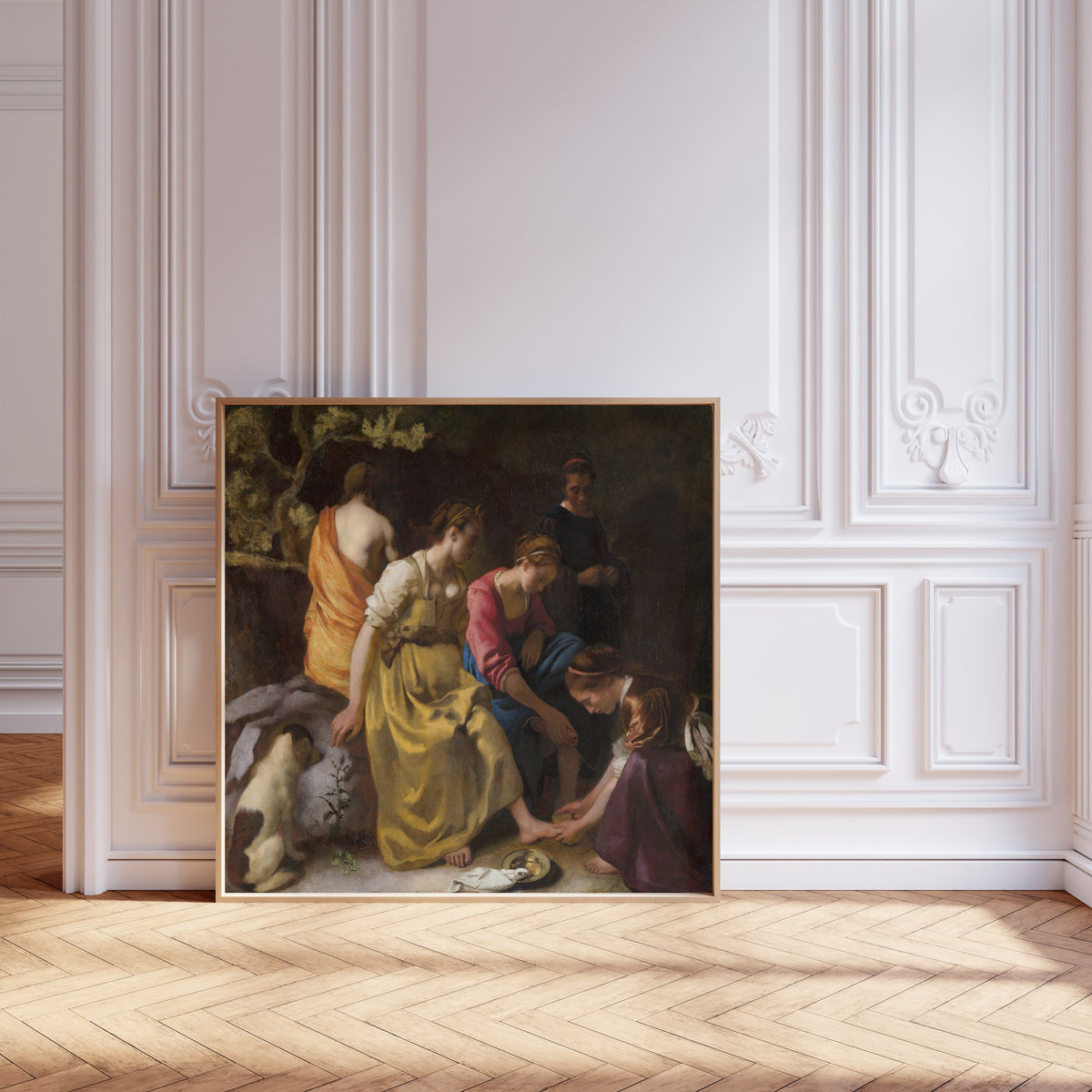 Framed art print of Diana and Her Nymphs by Johannes Vermeer, leaning against pale pink panelling on a herringbone floor